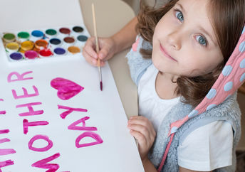 A young girl paints a Mother’s Day card.