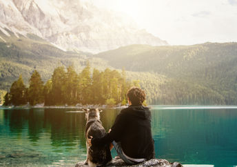 Man sitting with his dog in nature.