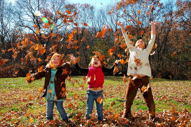 Children playing outside with leaves.