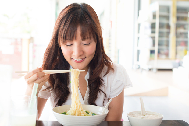 A woman enjoys a bowl of Ramen noodles