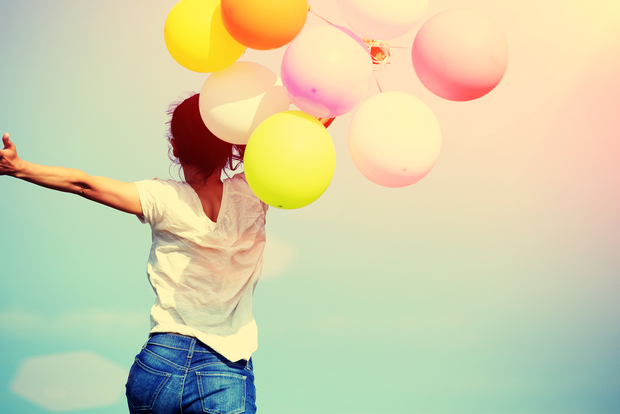 Happy woman jumping for joy with balloons