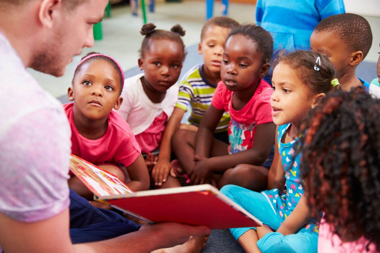 A volunteer reads a book to children. (Shutterstock)