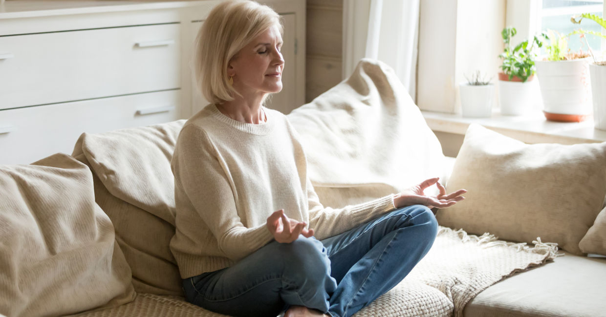 A woman meditates on her couch.