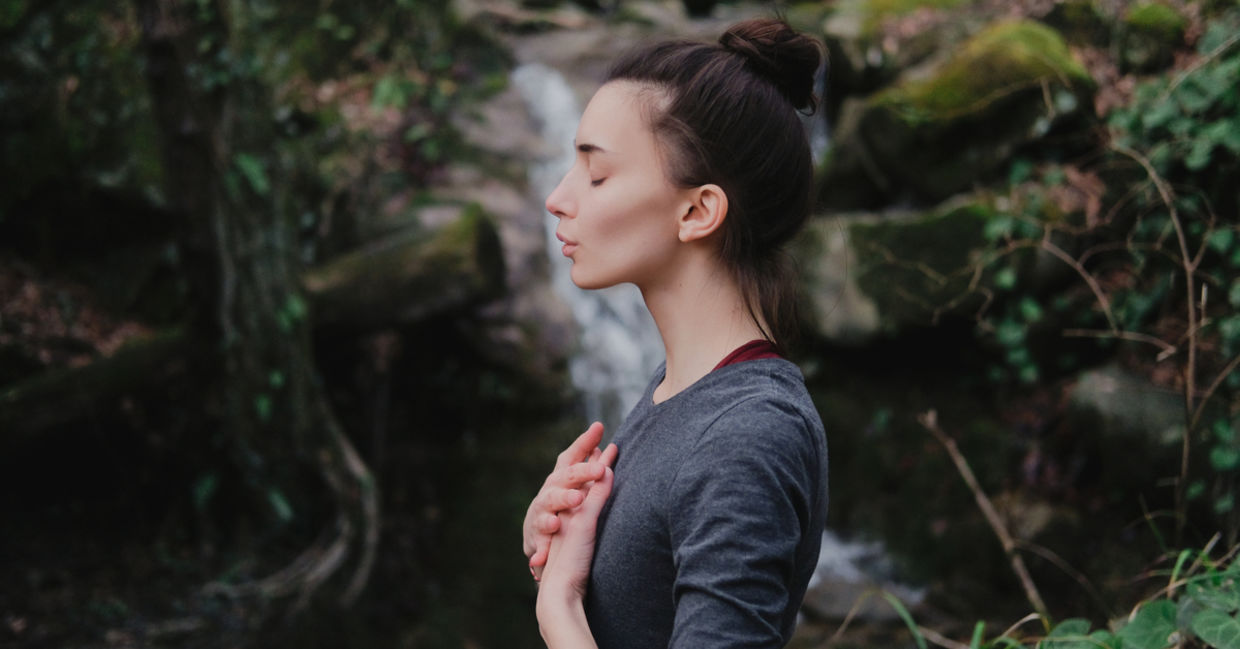 A woman practicing breathing in a forest.