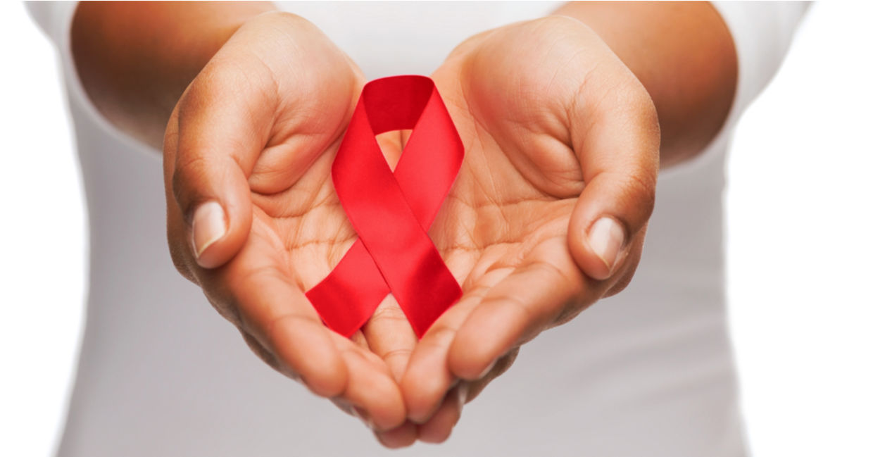 AIDS awareness ribbon in between two hands.