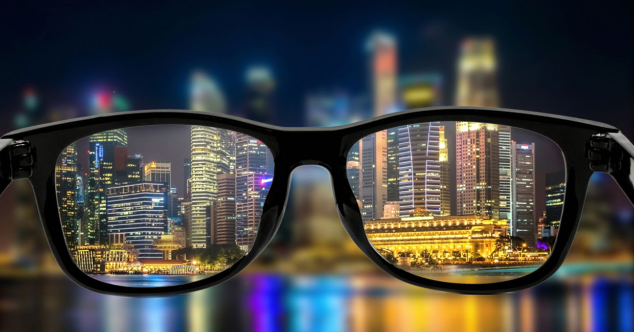 Looking through the lenses of glasses and seeing a bright cityscape at night.