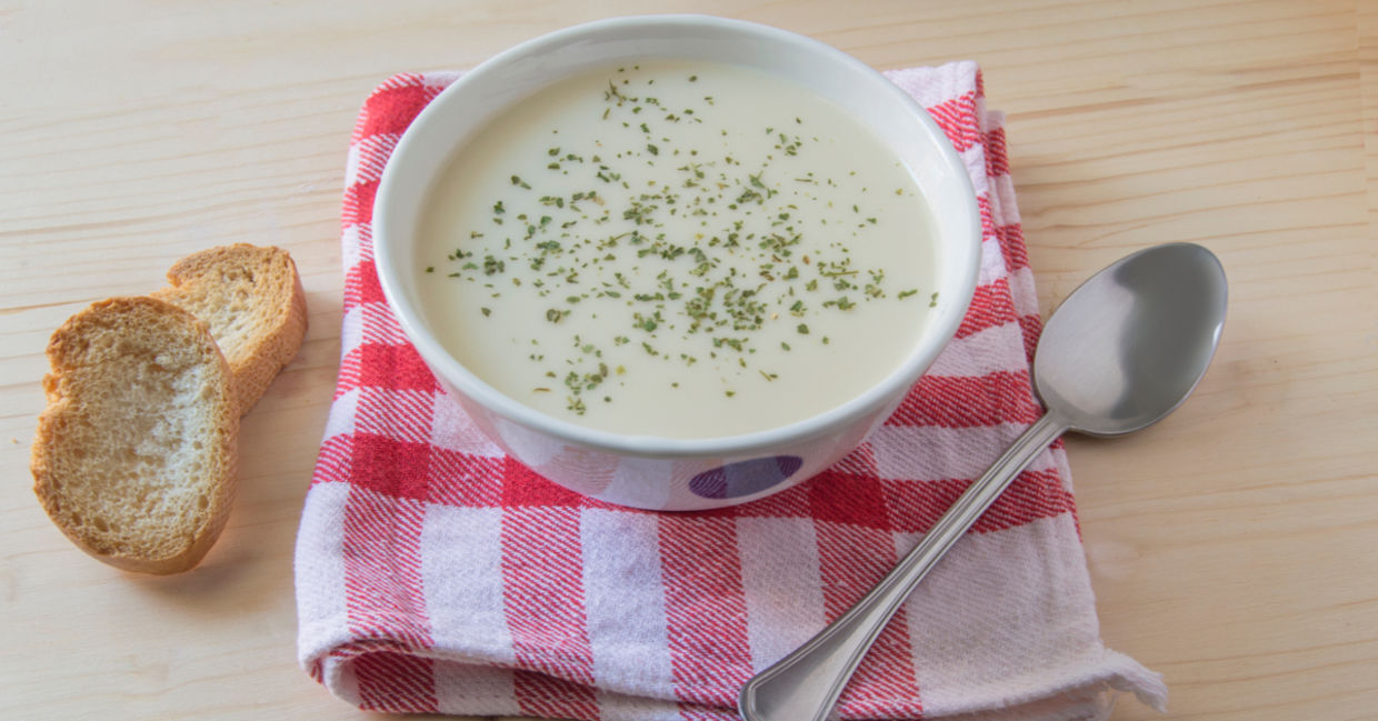 A bowl of vichyssoise served with sliced baguette.