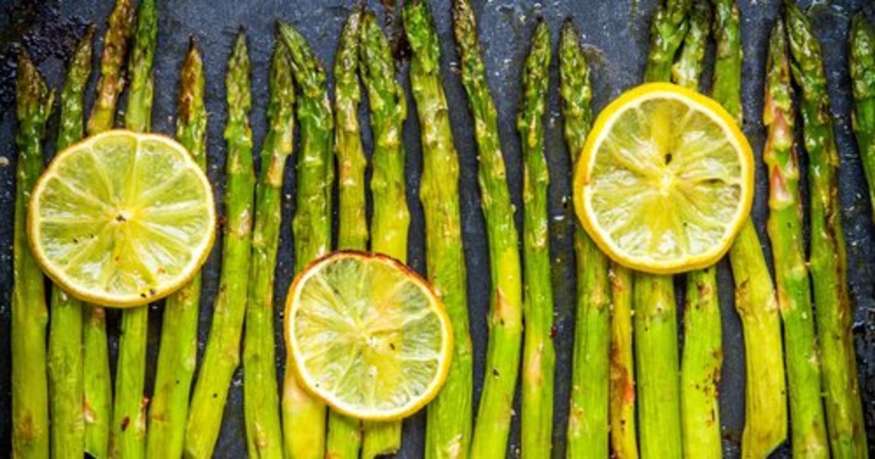 Baked asparagus is served with lemon slices.