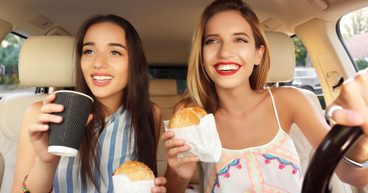 Young women eating fast food in a car.