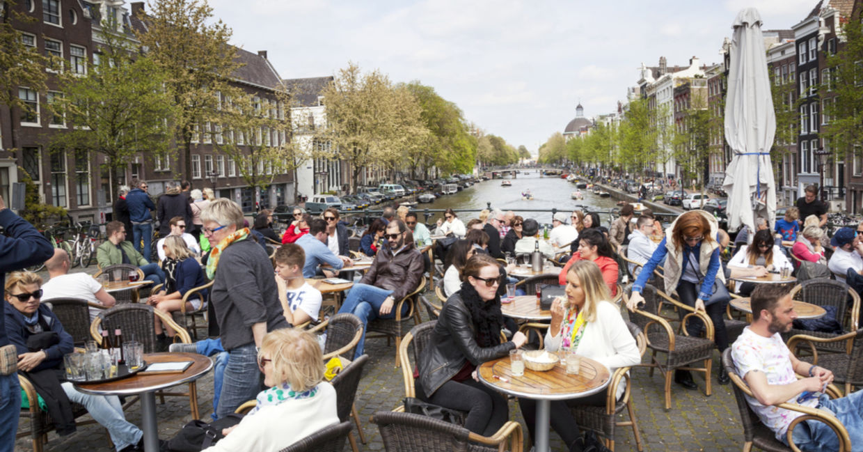 People enjoy a gezellig life sitting in an outdoor cafe Amsterdam.