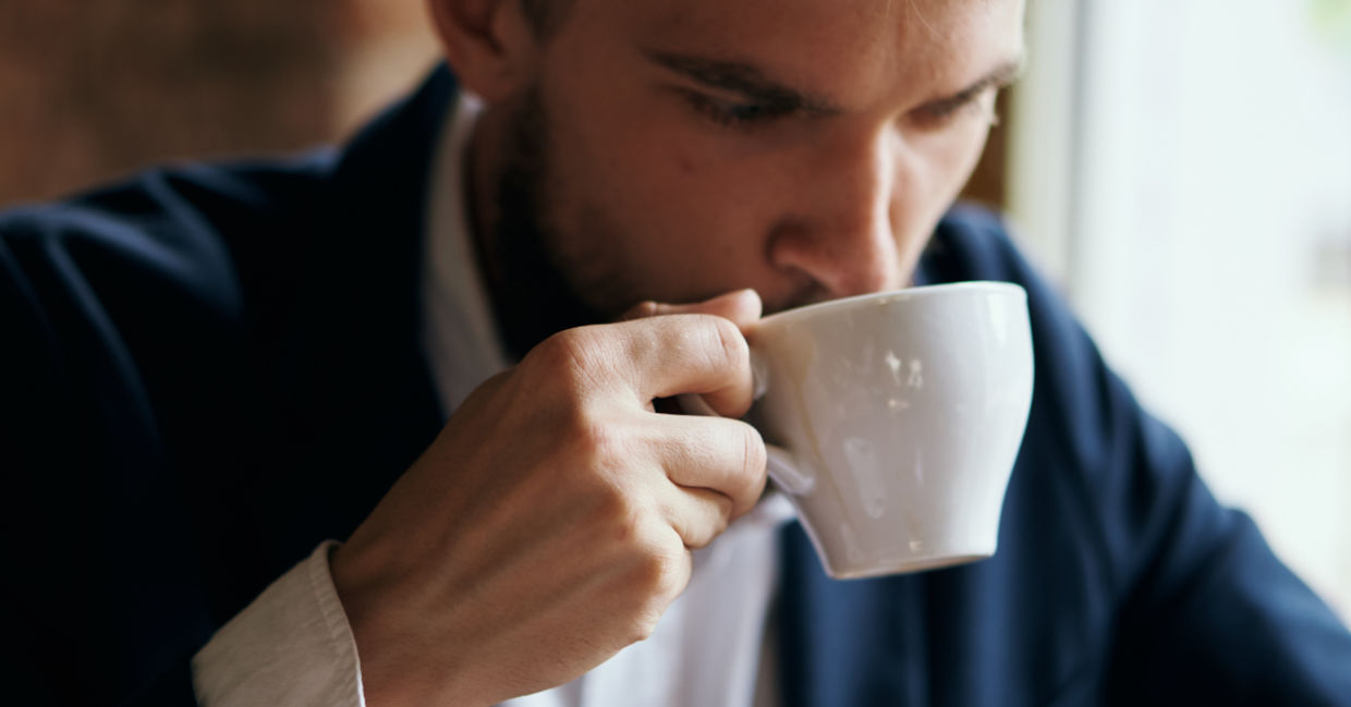 Portrait of a man enjoying a warm beverage in a porcelain cup.