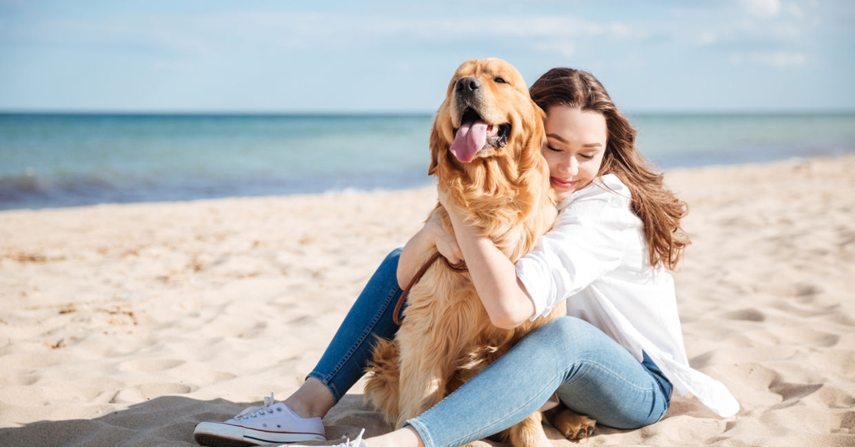 Woman sitting with dog on beach