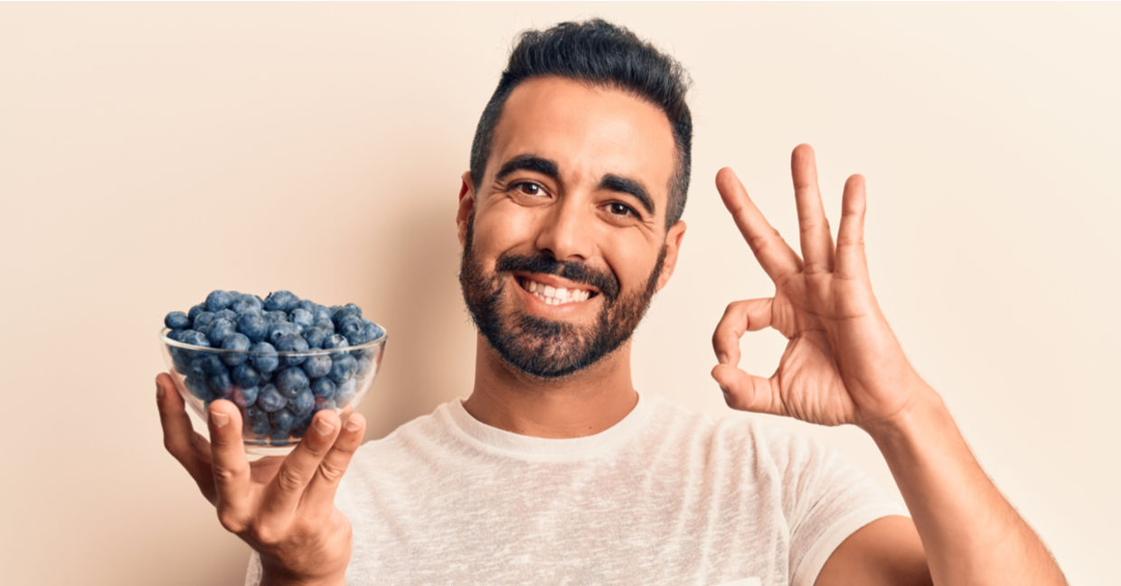 A man holds a bowl of gut-friendly blueberries.