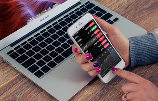 A woman checks a financial app on her iPhone
