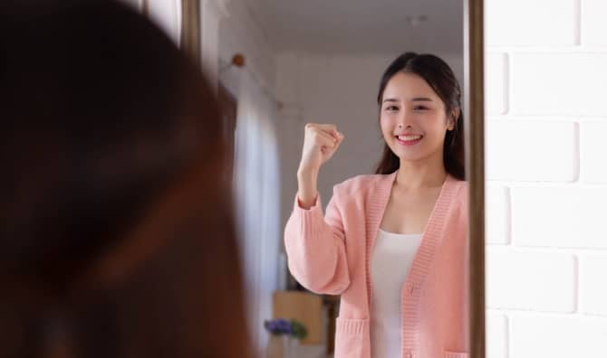 A woman smiles while looking at her reflection.