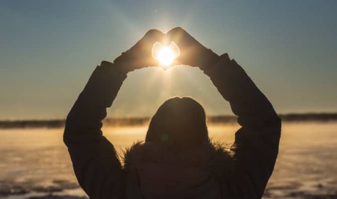 A woman makes a heart with her hands.