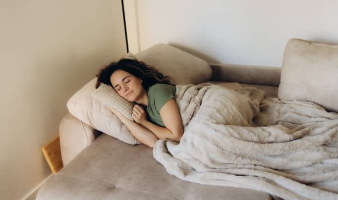 A woman rests peacefully under a warm blanket.