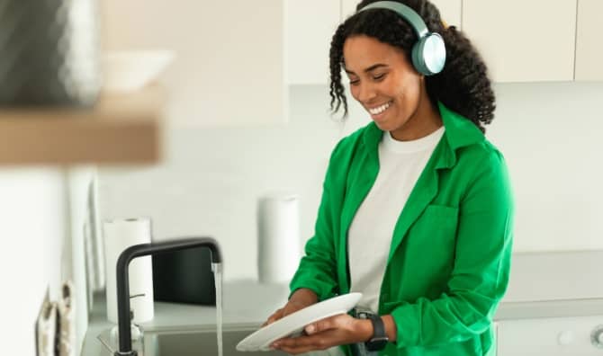 Woman listening to an audiobook while doing dishes.