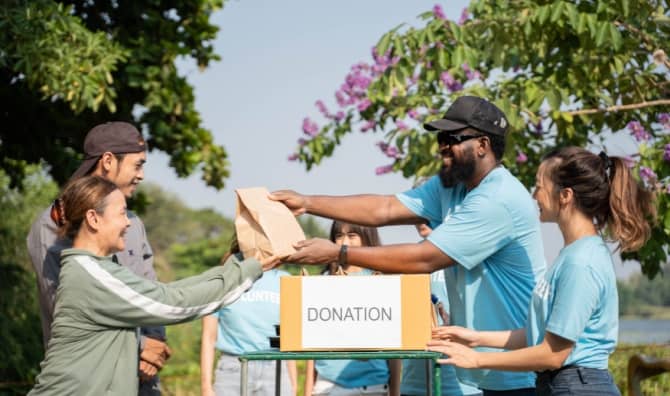 A team of volunteers with a donation box outdoors.