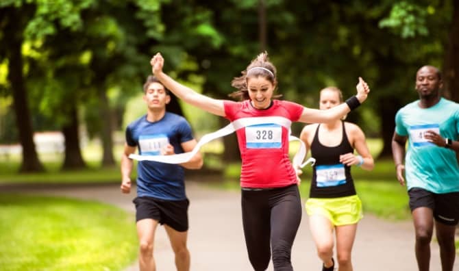 A woman runs in the crowd and crosses the finish line.