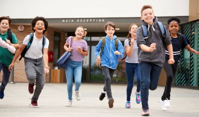 A group of students running out of a school building at the end of class.
