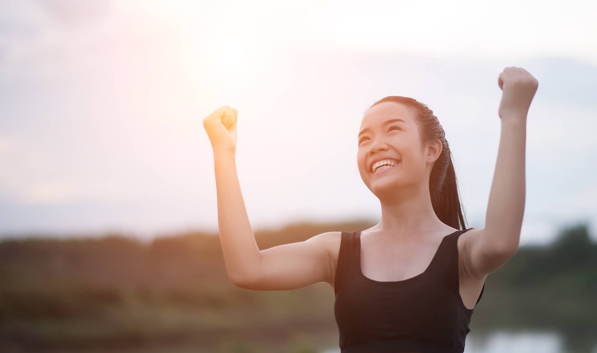 A smiling athletic woman outstretches her arms.