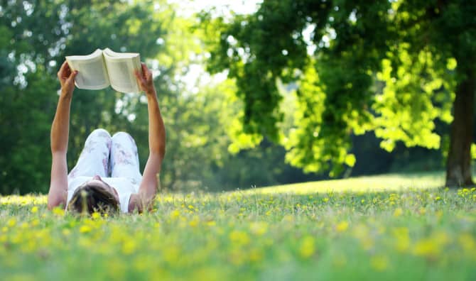 Woman lying on the grass reading a book