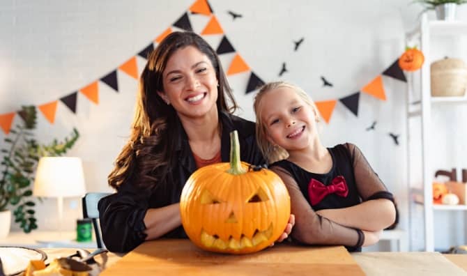 A mother and daughter proudly display their carved jack-o'-lantern.