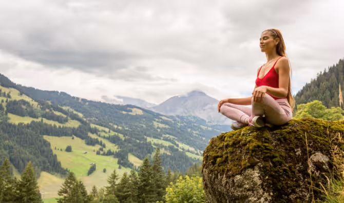 A woman meditates on a mountain.