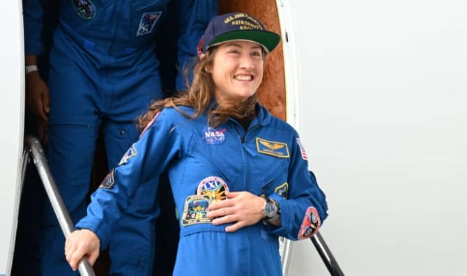 Christina Koch stands and smiles during the Artemis-02 crew return ceremony.