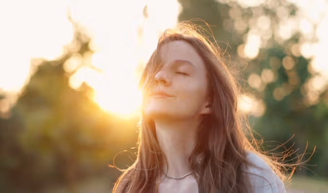 A relaxed woman outside with her hair blowing in the wind.