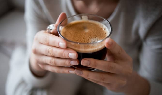 Holding a cup of hot coffee.
