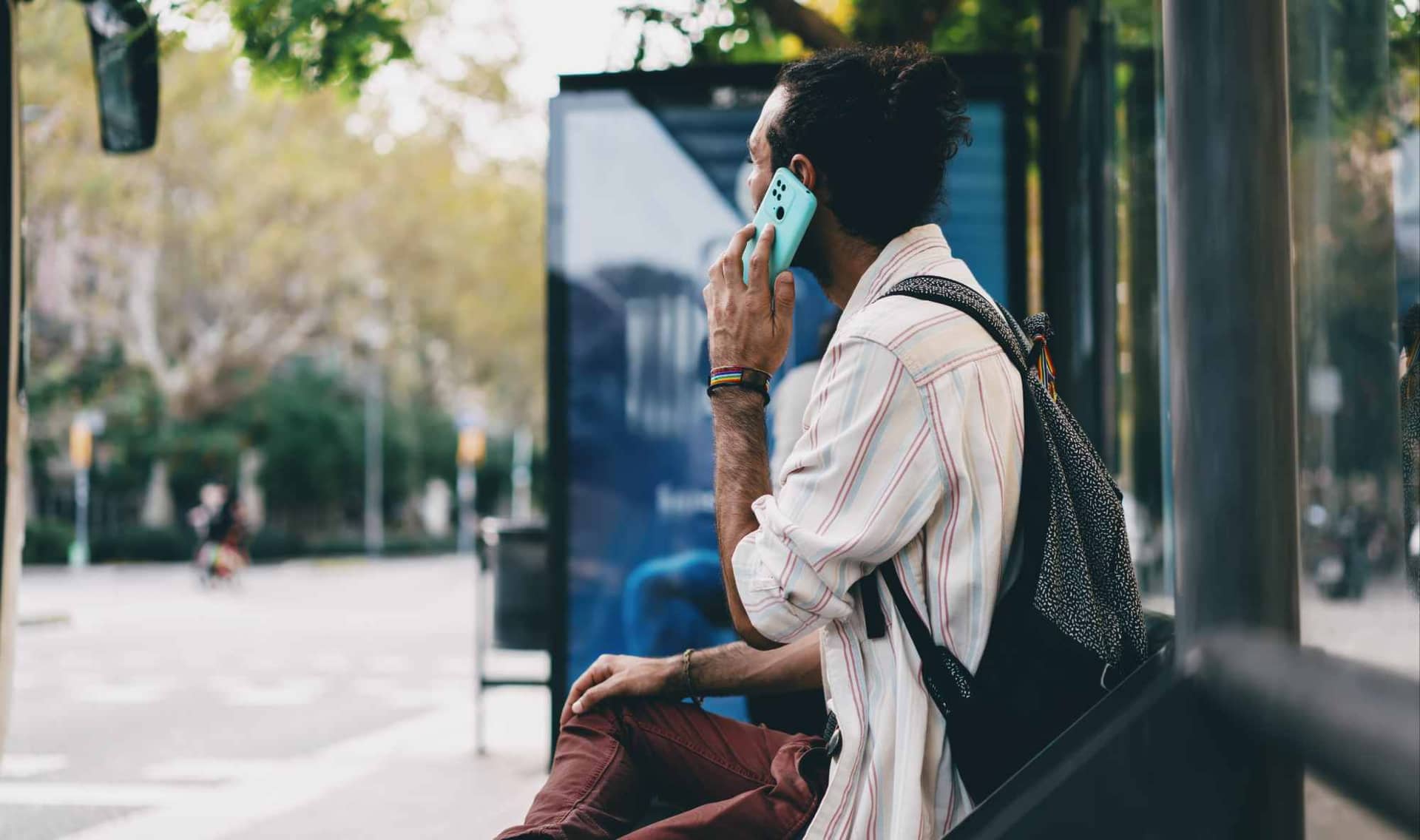 A man sits at a bus stop.
