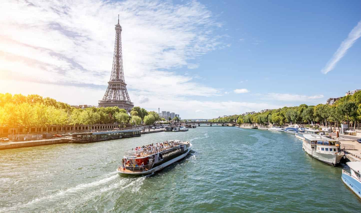 A view of the Eiffel tower and Seine river with a tourist boat in Paris.