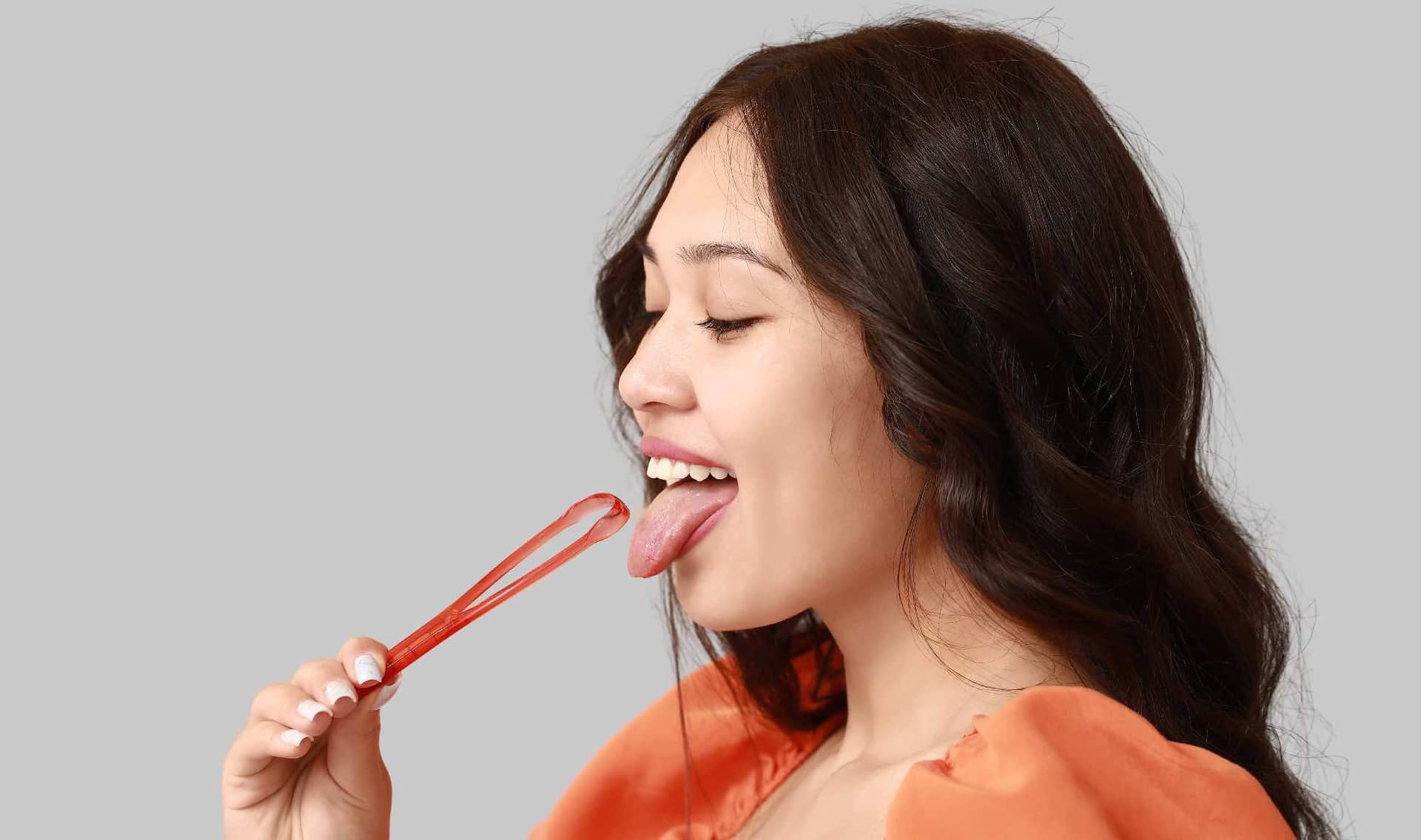 A woman holds a tongue scraper.