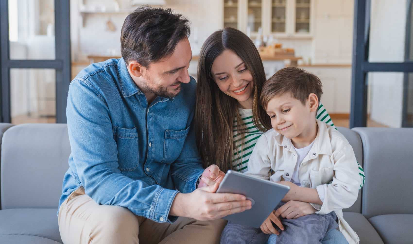 A young family looks at a digital tablet together at home.