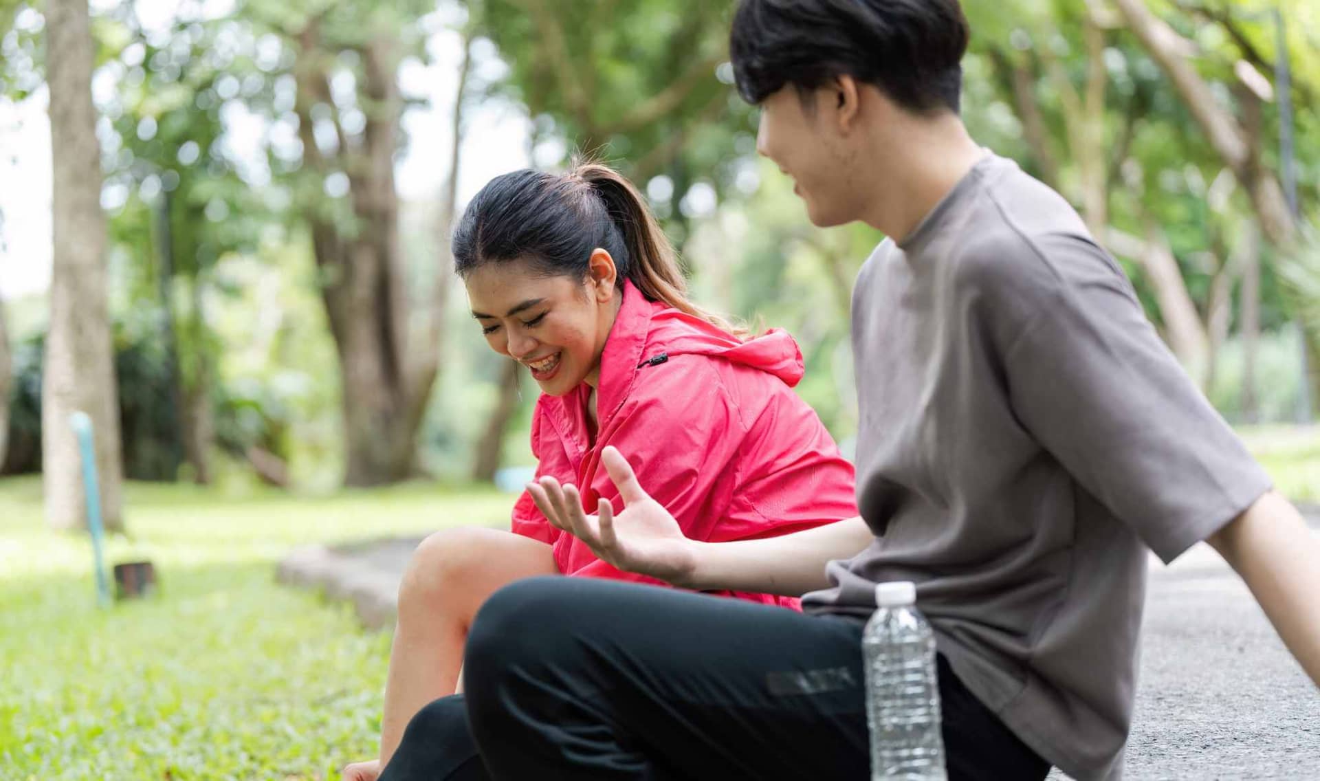 Two people enjoy a relaxing moment in a park after exercise.