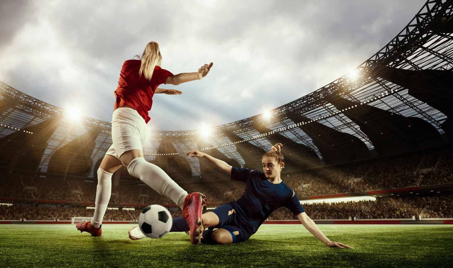 Two women play football in a stadium.