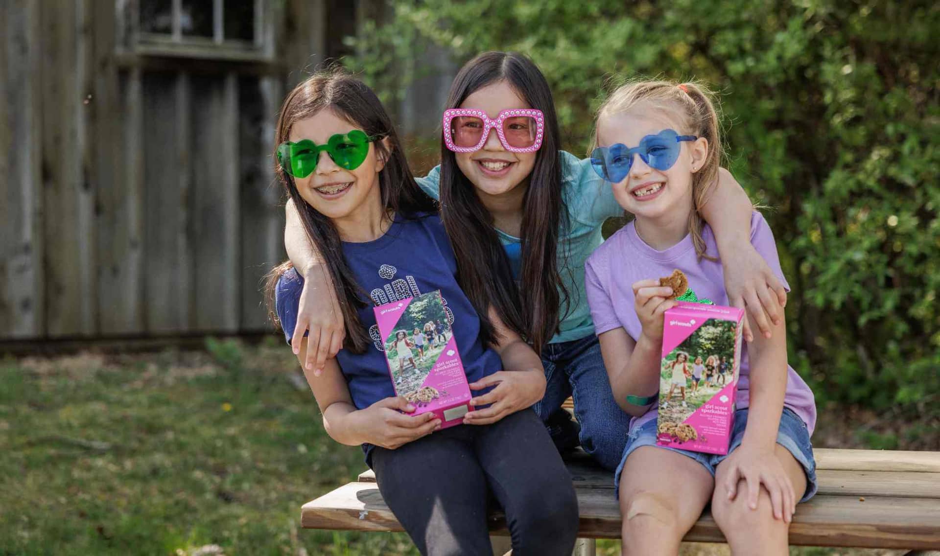 Three Girl Scouts holding a box of new cookies.
