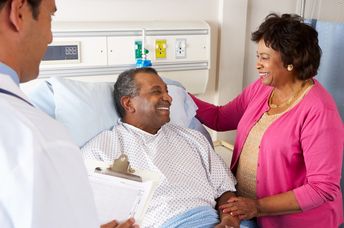 Doctor Talking To Senior Couple On Ward