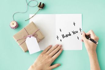A woman writes thank you on a card