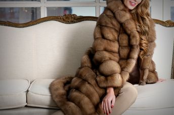 Woman in fur coat, close up, on the sofa, fur texture