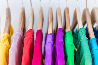Shirts in different colors hang in a closet.