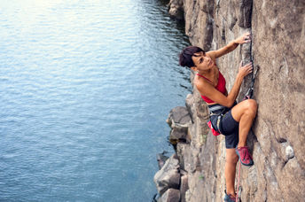 take a risk - Female climber dangles from the edge of a challenging cliff