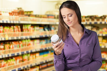 Woman reading food label in supermarket