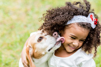 Girl being licked by her pet dog.