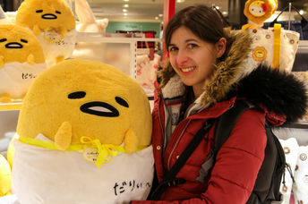 Young woman holds a large Gudetama plush toy.