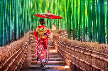 A Japanese woman in kimono enjoys exercise as she walks through a bamboo forest.