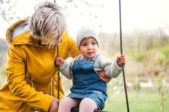 Grandmother helping a little kid on a swing