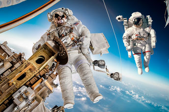 The International Space Station in outer space with two astronauts floating outside.